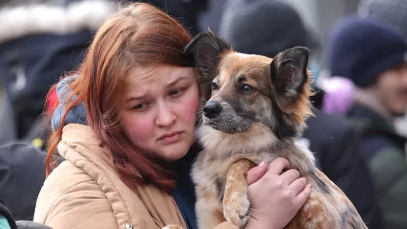 Jovem abraça seu cachorro enquanto eles aguardam para cruzar a fronteira entre a Ucrânia e a Polônia. Crédito: Getty Images